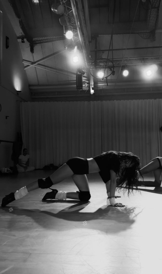 Black and white photograph of a dancer crawling in floorwork choreography on a studio stage.